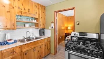 Une cuisine compacte avec des meubles en bois, un évier en acier inoxydable et une cuisinière noire.