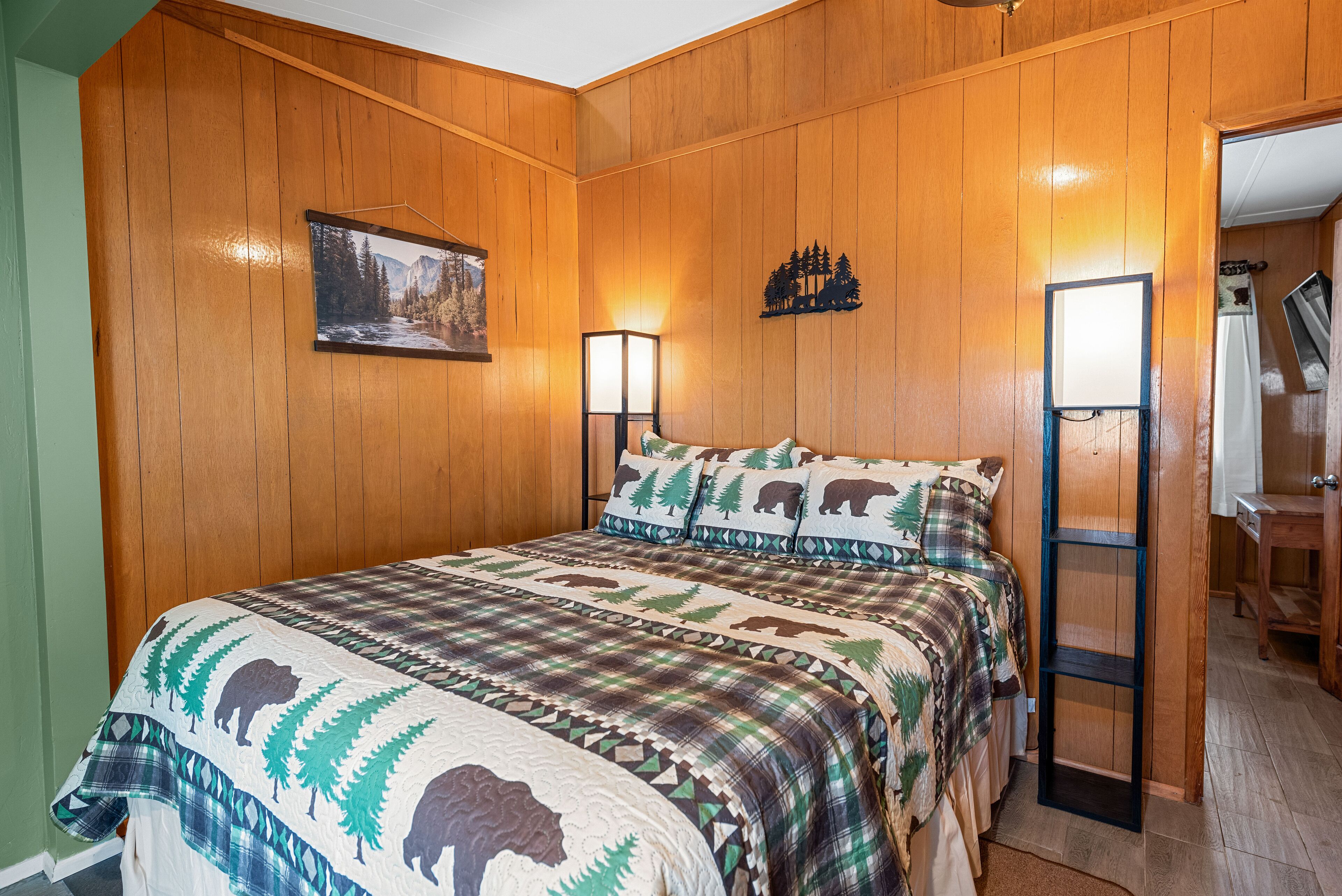 Une chambre à coucher avec un lit, des murs en bois, un tableau et une table de chevet.