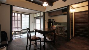 A traditional Japanese-style room with tatami flooring, a low wooden table, and a sliding door leading to a kitchen area. - Kiyomizu Birodo-An (Kyoto)