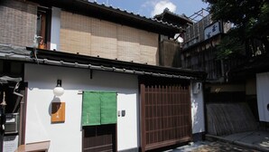 A traditional Japanese building with a tiled roof, a wooden gate, and a green cloth hanging on the wall. - Kiyomizu Birodo-An (Kyoto)