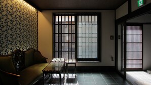 A traditional Japanese room with tatami flooring, a low table, and a sofa. - Kiyomizu Birodo-An (Kyoto)