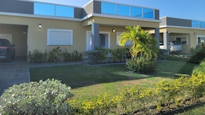 A modern two-story house with a garage, a well-maintained lawn, and a variety of plants. - Draxhall Marina Villa (St. Ann's Bay)