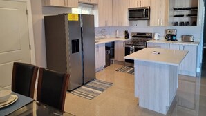 A modern kitchen with light wood cabinets, stainless steel appliances, and a central island. - Draxhall Marina Villa (St. Ann's Bay)