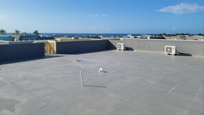 A rooftop terrace with a clear view of the sea, air conditioning units, and a tiled floor. - Draxhall Marina Villa (St. Ann's Bay)