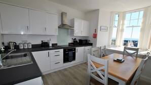 Une cuisine moderne avec des meubles blancs, un plan de travail noir et une table à manger en bois.