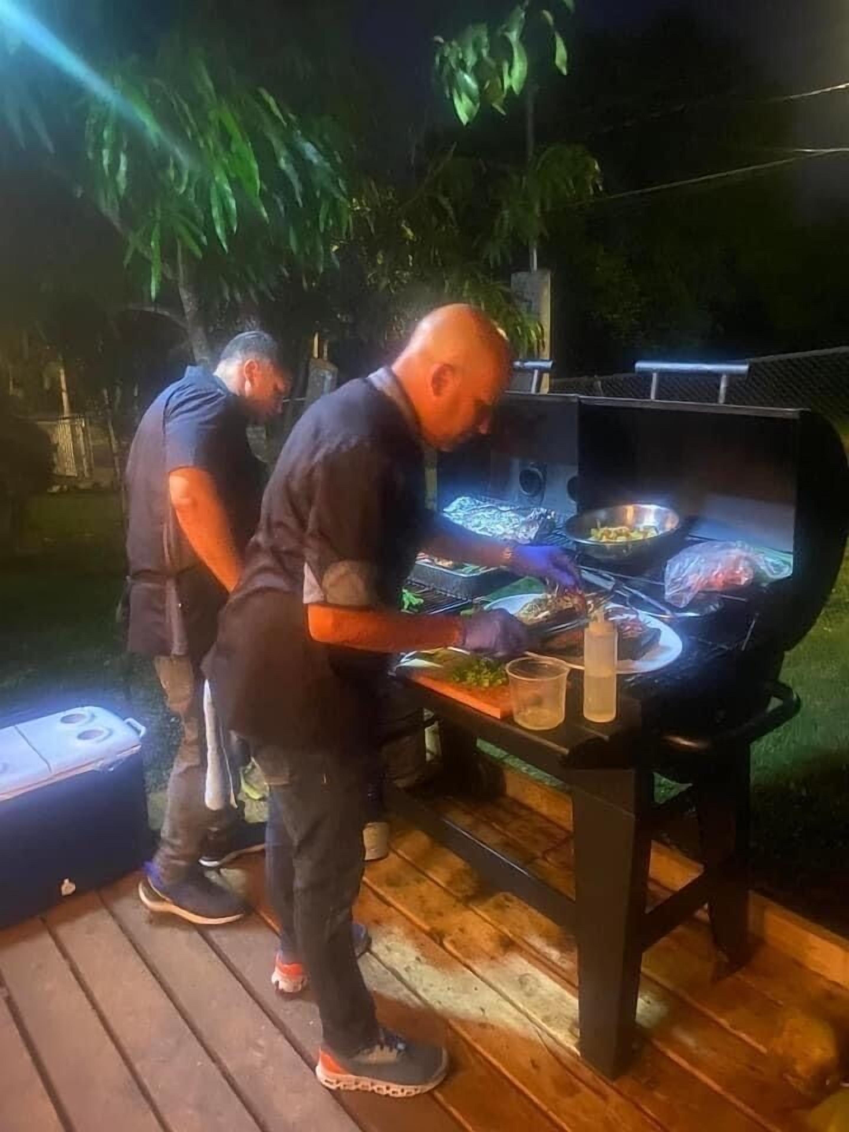 Un hombre asando comida en una barbacoa al aire libre.