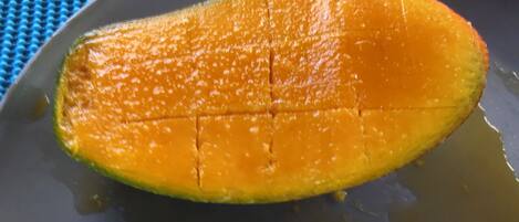 A mango sliced and placed on a dark plate.
