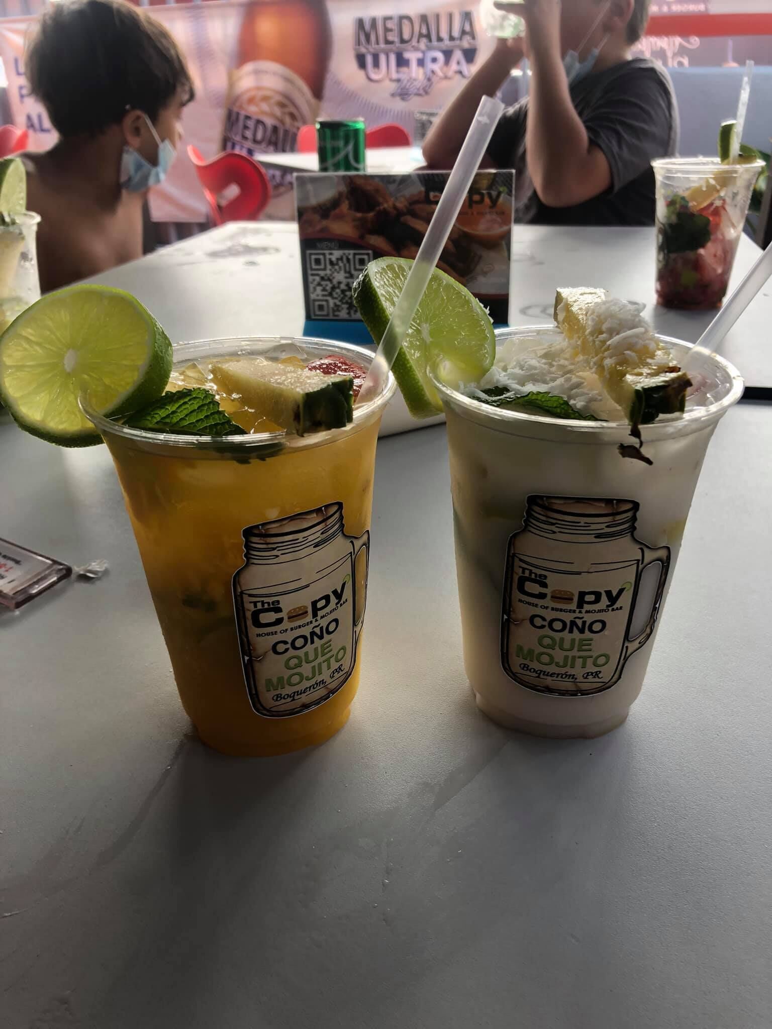 Deux boissons décorées de quartiers de citron vert et de feuilles de menthe, posées sur une table.
