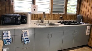A kitchen with a microwave, stove, sink, and wooden cabinets.