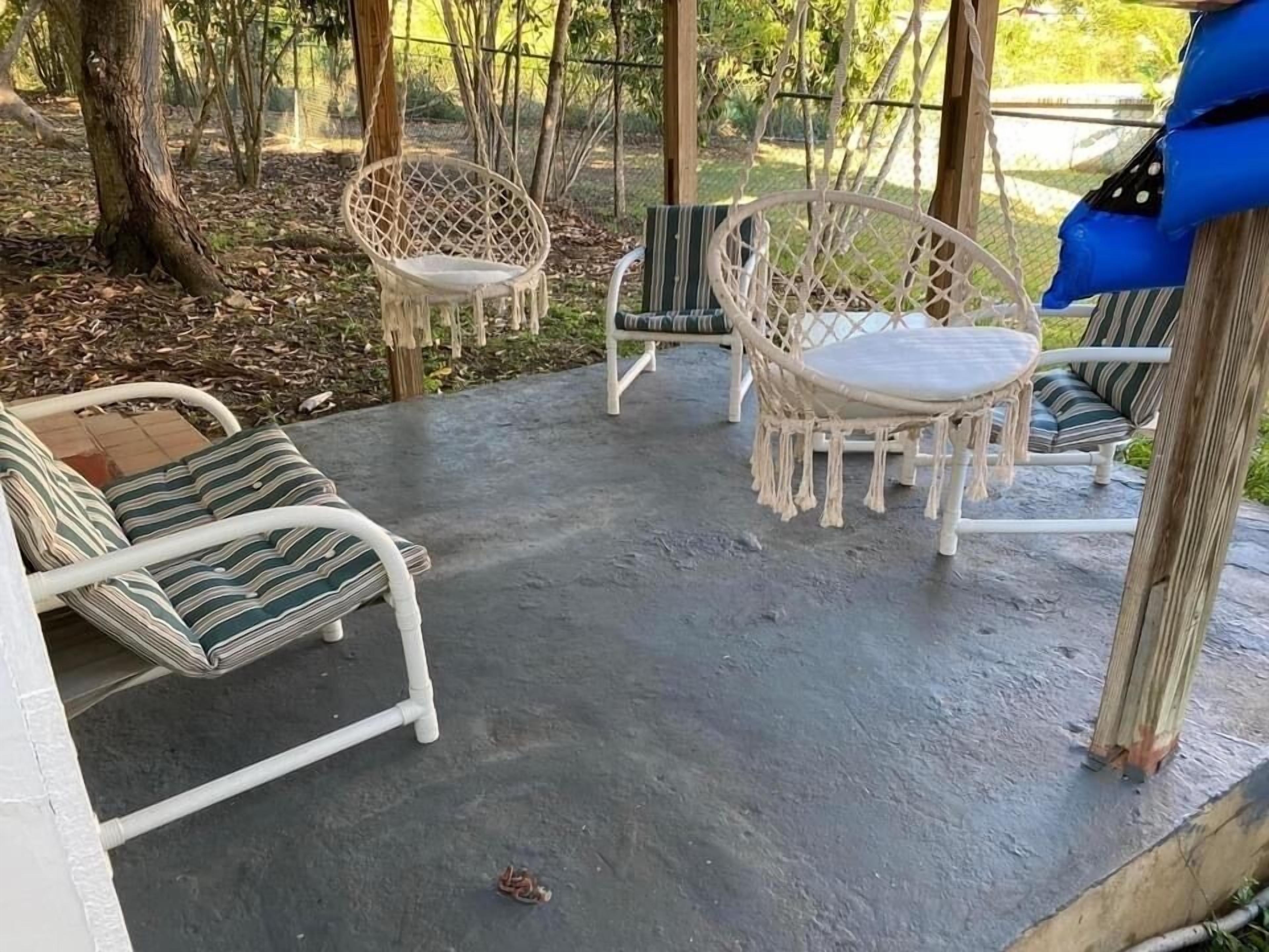 Un espacio de estar al aire libre techado con sillas de mimbre blanco y cojines a rayas.