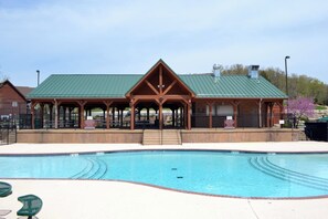 A swimming pool with a wooden pavilion in the background.
