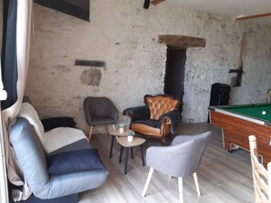 Una sala de estar acogedora con una mesa de billar, un sofá y dos sillones.