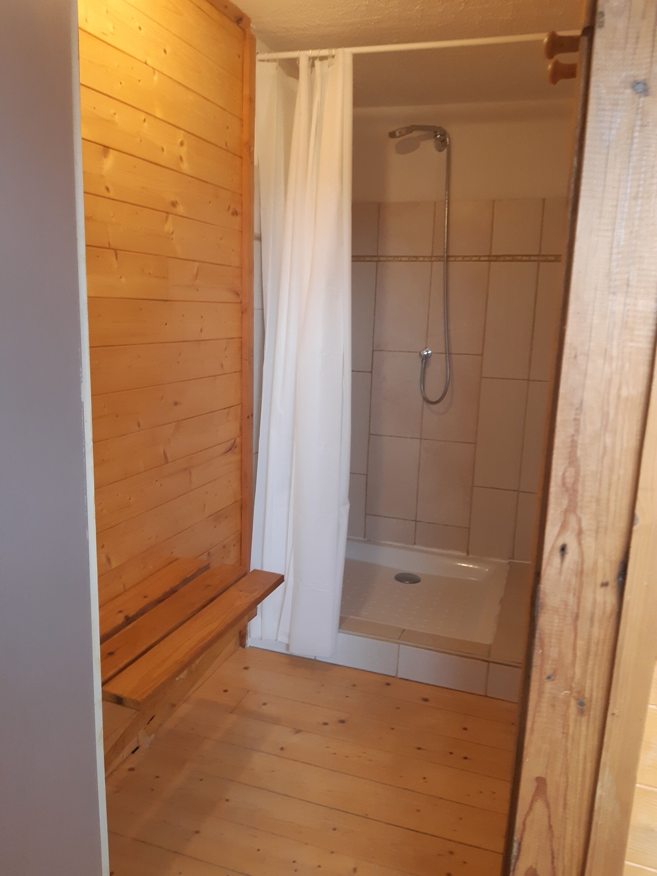 A wooden-paneled bathroom with a shower and a bench.