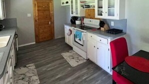 A compact kitchen with white cabinets, a built-in oven, and a red chair. - Charming Downtown Home on 5th street (Midlothian)