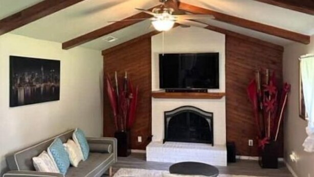 A modern living room with a fireplace, a television, and a ceiling fan. - Charming Downtown Home on 5th street (Midlothian)