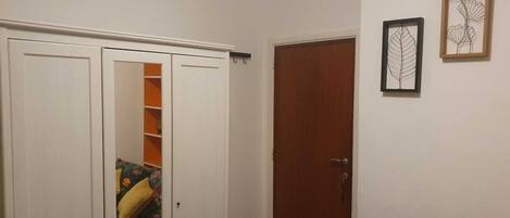 Une pièce avec une armoire blanche, une porte en bois et une œuvre d’art représentant une feuille, encadrée, accrochée au mur.