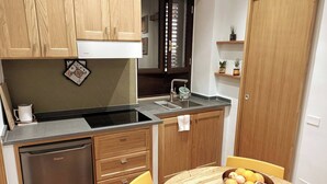 A compact kitchen with wooden cabinets, a built-in dishwasher, a sink, and a dining area with a table and chairs. - Holiday Home Sofia Palermo (Palermo)
