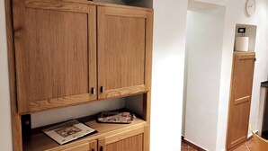 A wooden cabinet with a decorative item on top, a small shelf with a patterned object, and a clock on the wall. - Holiday Home Sofia Palermo (Palermo)