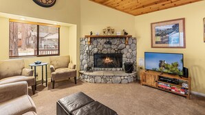 A cozy living room with a stone fireplace, a television, and comfortable seating. - Moonridge Heaven (Big Bear Lake)