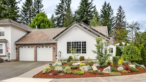 A two-story house with a garage, a front yard with a rock garden, and a large tree in the background. - Newly Built Maple Valley Vacation Rental w/ Patio! (Maple Valley)