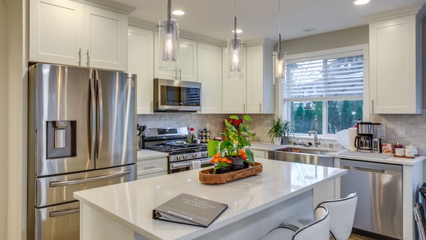 A modern kitchen with stainless steel appliances, a central island with seating, pendant lighting, and a view of the outdoors through a window. - Newly Built Maple Valley Vacation Rental w/ Patio! (Maple Valley)