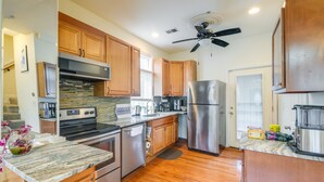 A kitchen with wooden cabinets, stainless steel appliances, a marble countertop, and a ceiling fan. - 5 Mi to US Capitol: Washington DC Townhome (Washington)