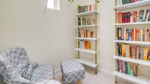 A room with a chair, ottoman, and a bookshelf filled with books. - 5 Mi to US Capitol: Washington DC Townhome (Washington)