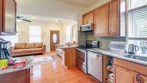 A kitchen with wooden cabinets, a stove, and a microwave. There is a window with blinds and a door leading to another room. - 5 Mi to US Capitol: Washington DC Townhome (Washington)