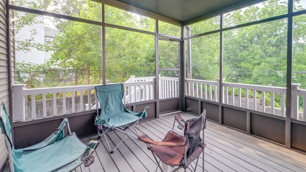 A covered porch with wooden flooring, white railings, and two green and one brown folding chairs. - 5 Mi to US Capitol: Washington DC Townhome (Washington)