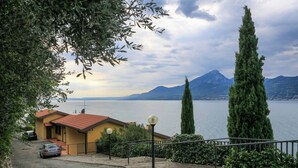 Un quartier résidentiel avec une maison, une voiture et une vue sur un lac et des montagnes.