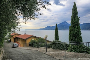 A residential area with a house, a car, and a view of a lake and mountains.