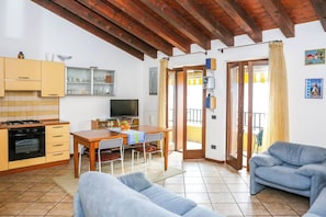 A kitchen with a TV, wooden cabinets, and a dining area with a table and chairs.