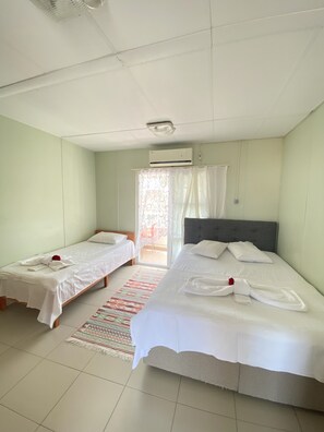 A hotel room with two single beds, a large bed, a ceiling fan, an air conditioning unit, a patterned rug, and a sliding glass door. - Sedef Pansiyon Apart Otel Sarkoy (Sarkoy)