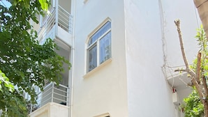 A residential building with a staircase leading to an upper floor, surrounded by potted plants and a small garden area. - Sedef Pansiyon Apart Otel Sarkoy (Sarkoy)