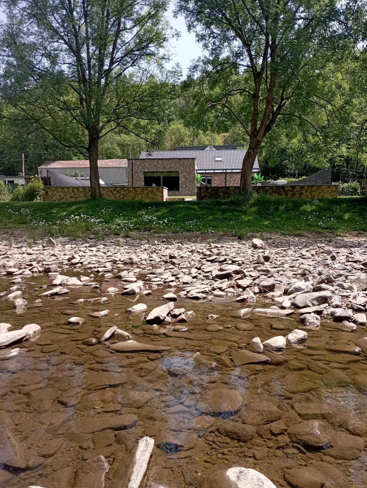 A rocky riverbed with a building in the background.