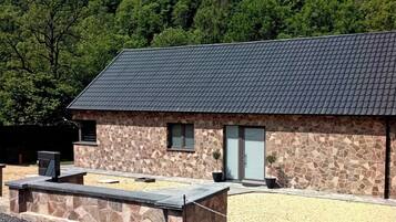 Set amidst lush greenery, this building features a small entrance and a gravel driveway leading to a paved area.