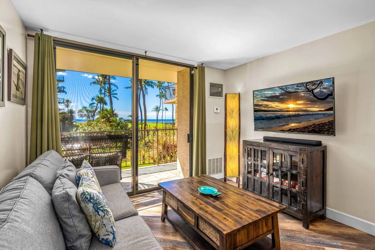 A living room with a sofa, coffee table, and a painting of a sunset.