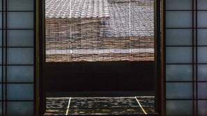 Una habitación japonesa tradicional con suelo de tatami, paneles shoji y techo de madera bajo.