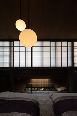 A room with two beds, a wooden ceiling, and a large window with a view of greenery. - Shinmichi Ayame-An (Kyoto)