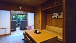 Una habitación con una mesa de madera, sillas, un banco, un reloj y vistas al exterior.