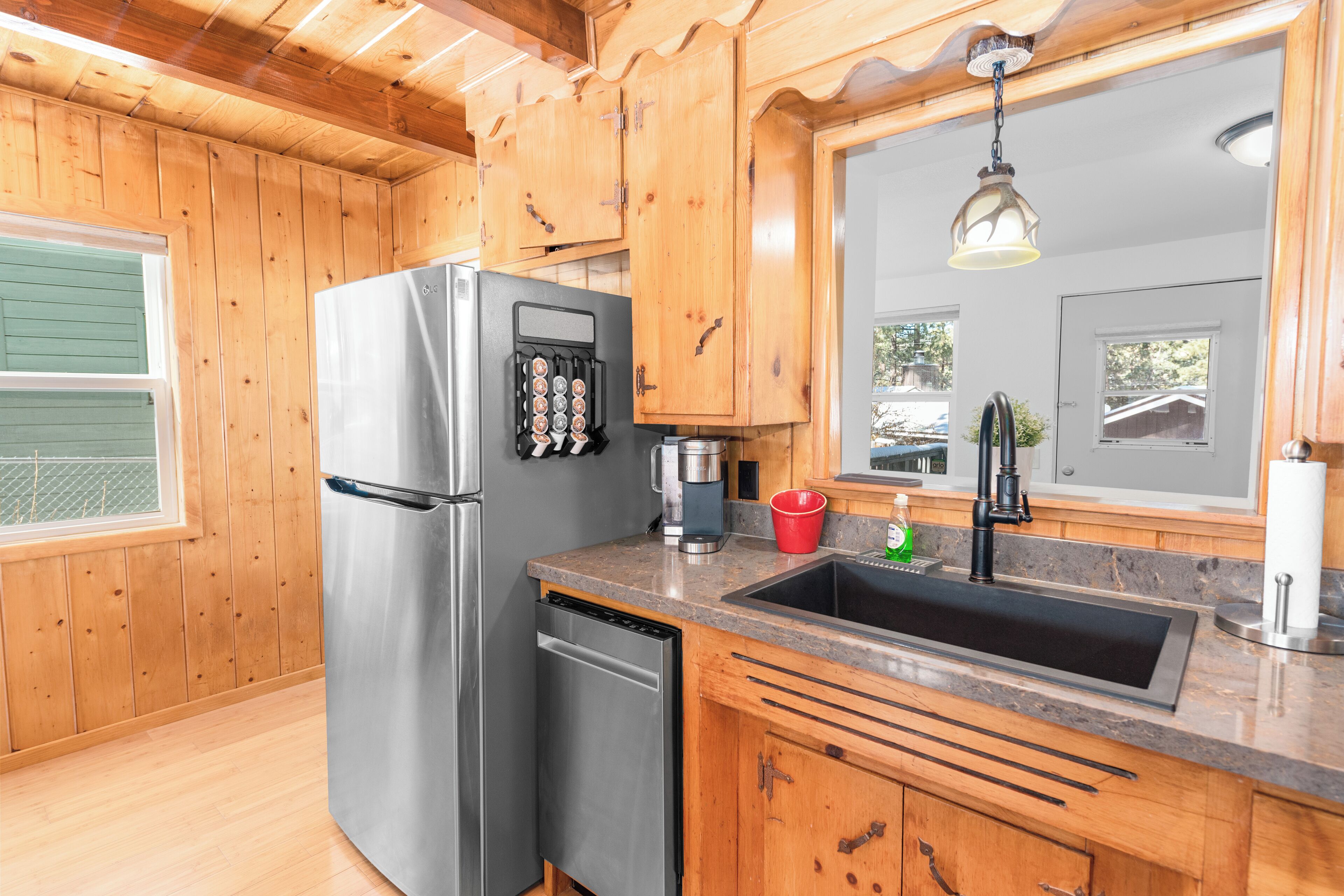 A kitchen with wooden cabinets, stainless steel appliances, a granite countertop, and a window with a view.