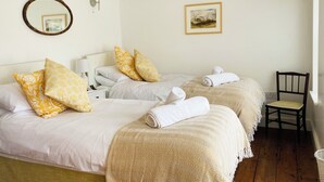 Ett hotellrum med två sängar, en stol, en spegel, en lampa och en inramad tavla på väggen.