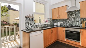 Een moderne keuken met houten kastjes, een zwart aanrecht en een betegelde achterwand.