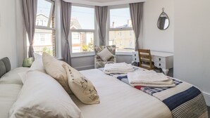 Een slaapkamer met een groot bed, een bureau en twee ramen.