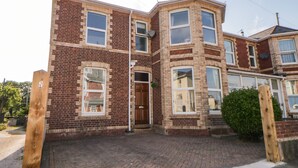 Een tweelaags bakstenen huis met een voordeur, twee ramen op de begane grond en een klein portaal.
