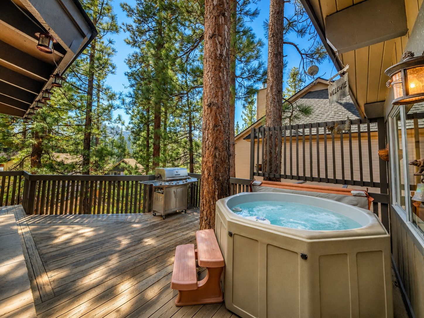 Una terraza de madera con jacuzzi, mesa de picnic y parrilla.