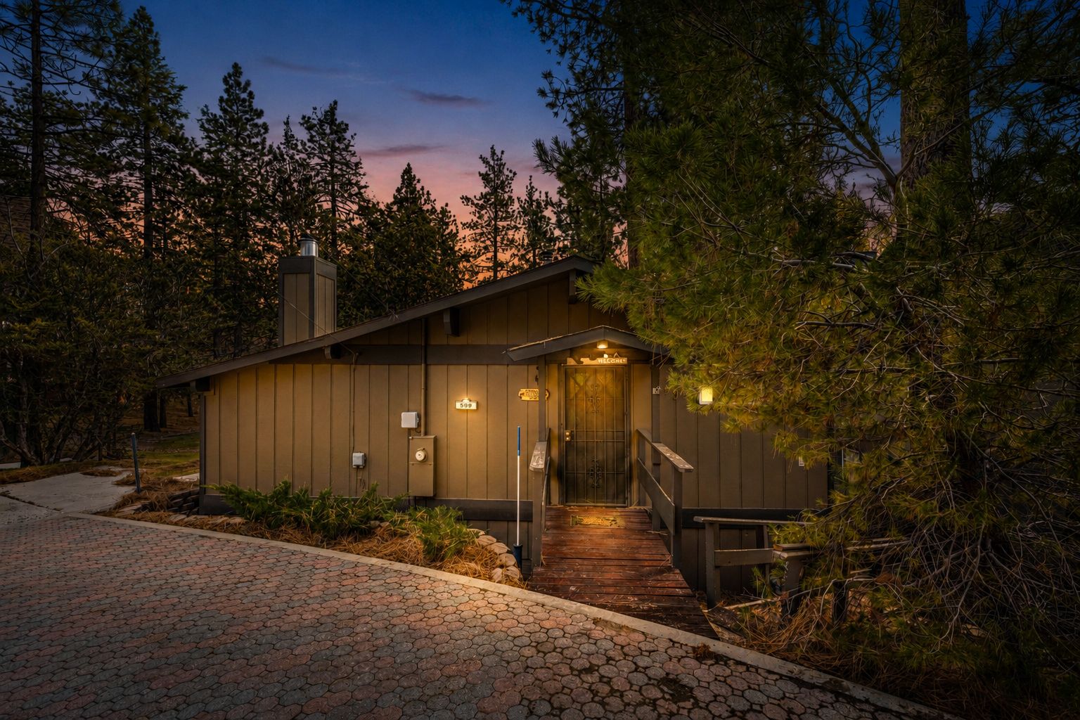 A lodge with a wooden exterior, a covered entrance, and a paved driveway.