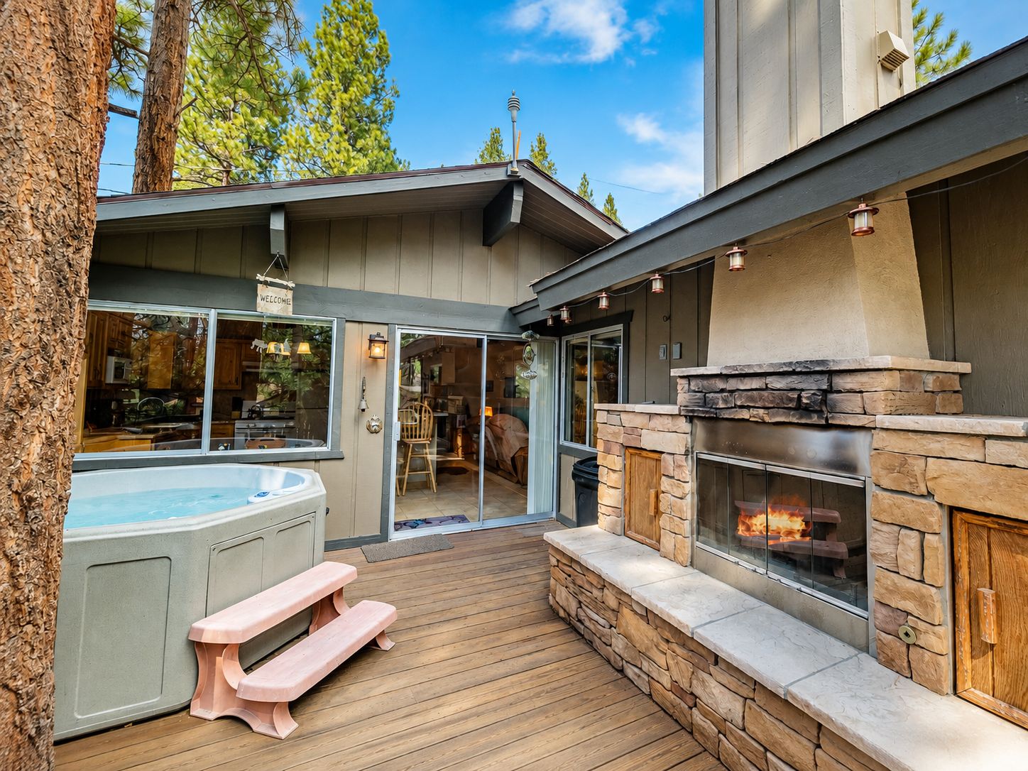 Ein Whirlpool, Sitzgelegenheiten im Freien und ein Kamin auf einer Holzterrasse.