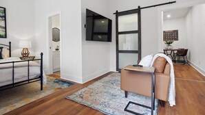 Un dormitorio moderno con cama, escritorio, silla y un espejo grande.