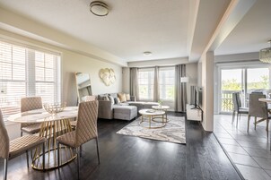 A modern living room with a dining area, a sectional sofa, and a large window with blinds.